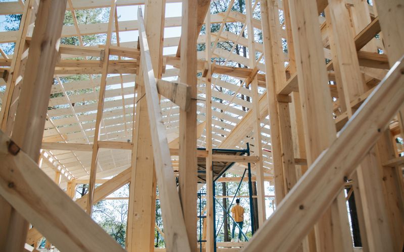 Ossature bois d'une maison en construction entourée d'échafaudages