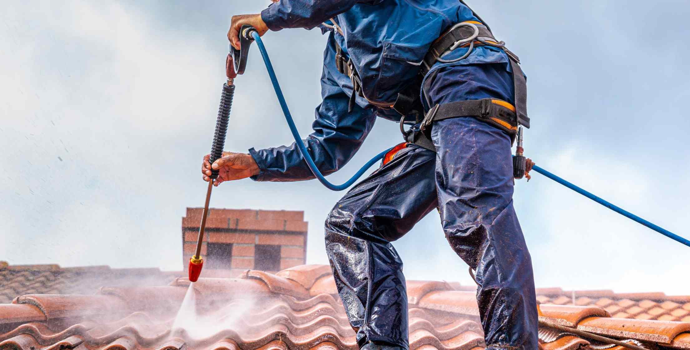 Couvreur nettoyant une toiture couverte de mousse