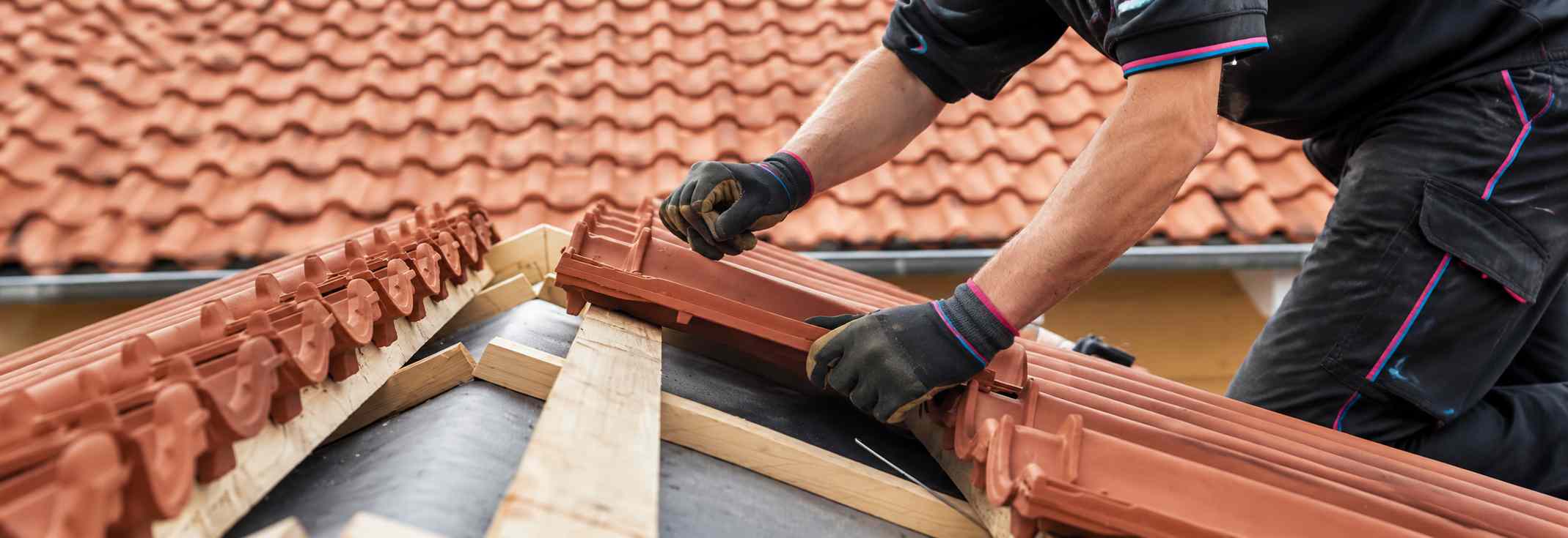 Ouvrier couvreur remplaçant des tuiles endommagées sur une toiture