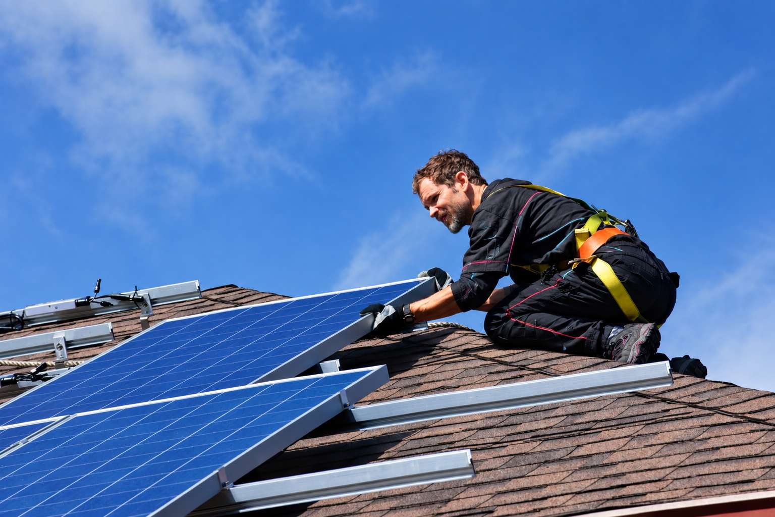 Ouvrier posant des panneaux solaires sur une toiture pour une installation en autoconsommation